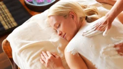 Iszappakolás - Nő hátát fehér kozmetikai iszappal kenik.