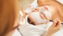 Iszappakolás - Nő arcára fehér iszap maszkot visznek fel ecsettel.