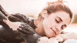 Iszappakolás - Nő fekete iszappakolással a hátán pihen masszázs közben.